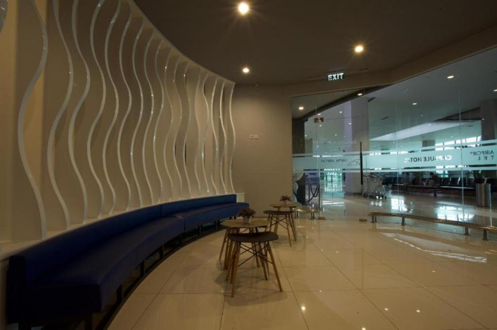 a lobby with chairs and tables in a building at Passgo Digital Airport Terminal 3 Soekarno Hatta in Tangerang