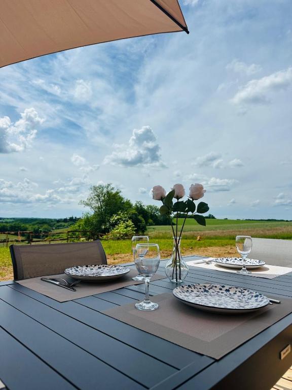 une table avec des assiettes et des verres et un vase avec des fleurs dans l'établissement La maison dans la prairie gîte marguerite, à Saint-Avit-Sénieur