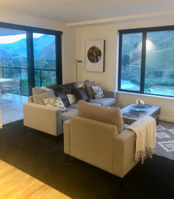 a living room with a couch and a table at Modern Luxury Condo Shotover Views in Queenstown