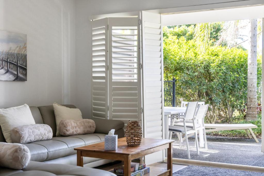 a living room with a couch and a table at Oaks Pacific Blue Port Stephens. Apartment overlooking the Pool in Salamander Bay