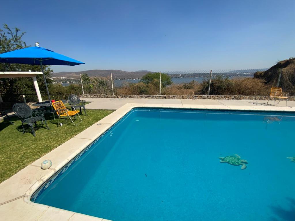 a blue swimming pool in a yard with an umbrella at Casa Fátima in Tequesquitengo