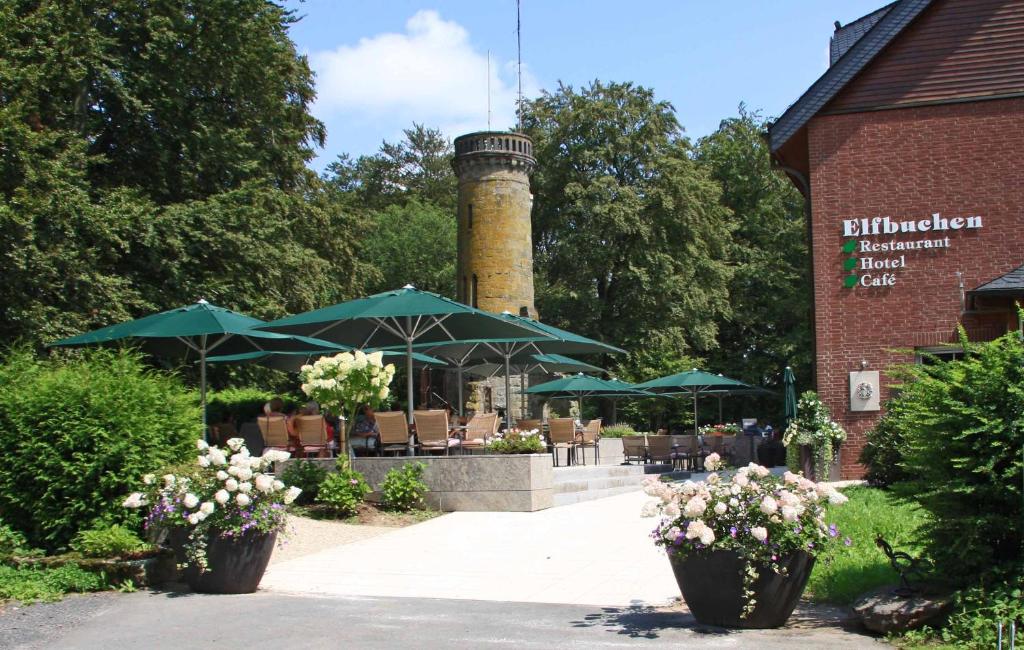 a building with a lighthouse with tables and umbrellas at Hotel Elfbuchen in Kassel