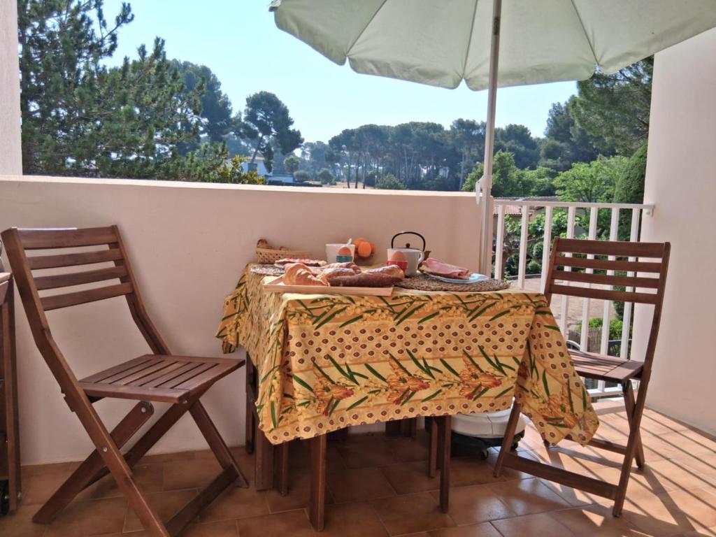 - une table avec 2 chaises et un parasol sur une terrasse couverte dans l'établissement Les Pins de la Mer, à Sanary-sur-Mer