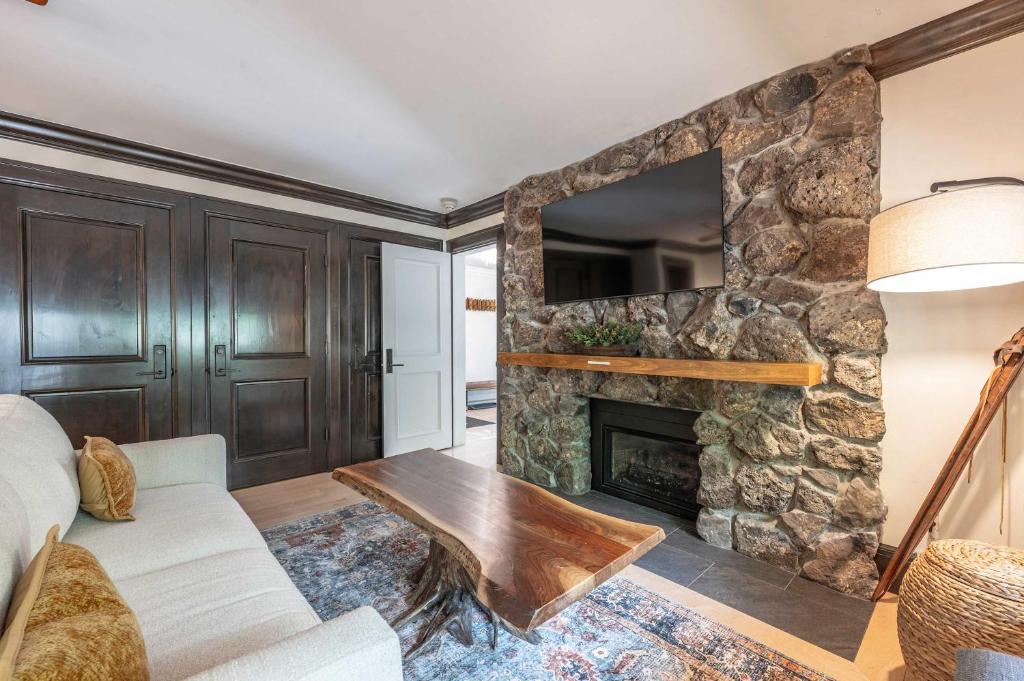 a living room with a stone fireplace with a tv at New Listing 3 BR 3 BA Aspen Condo near Gondola in Aspen
