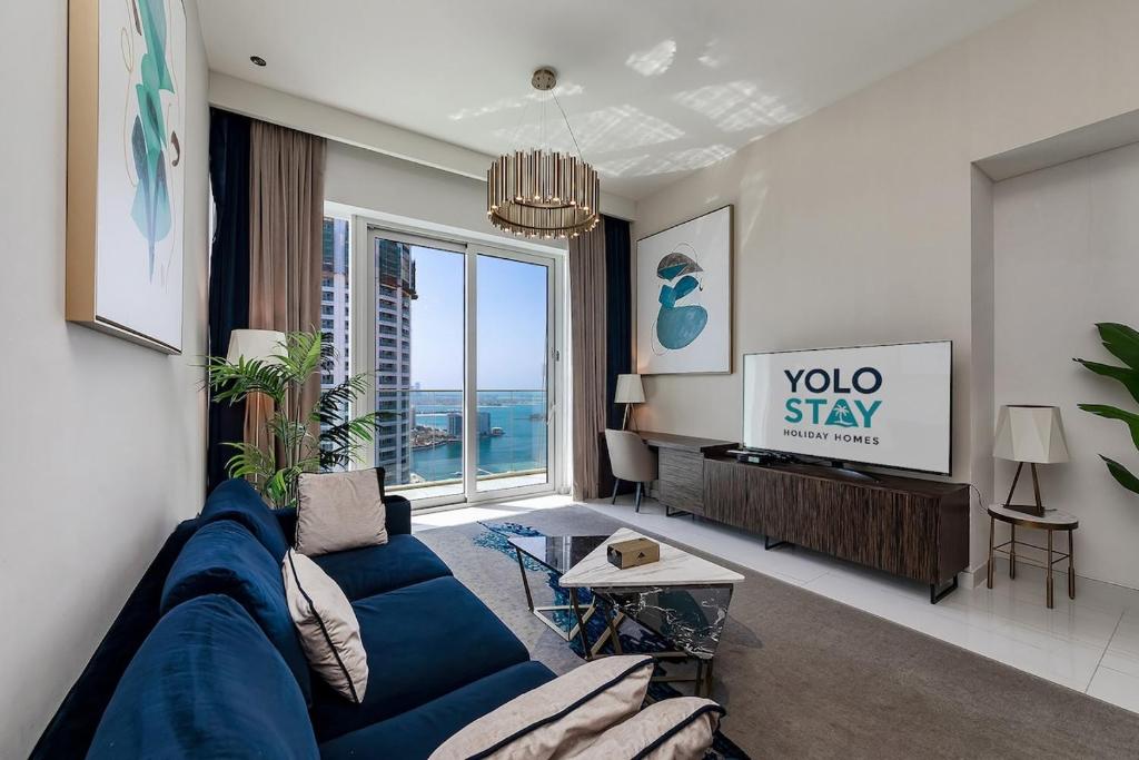 a living room with a blue couch and a tv at Fabulous 2BR Apartment with Palm View in Media City in Dubai