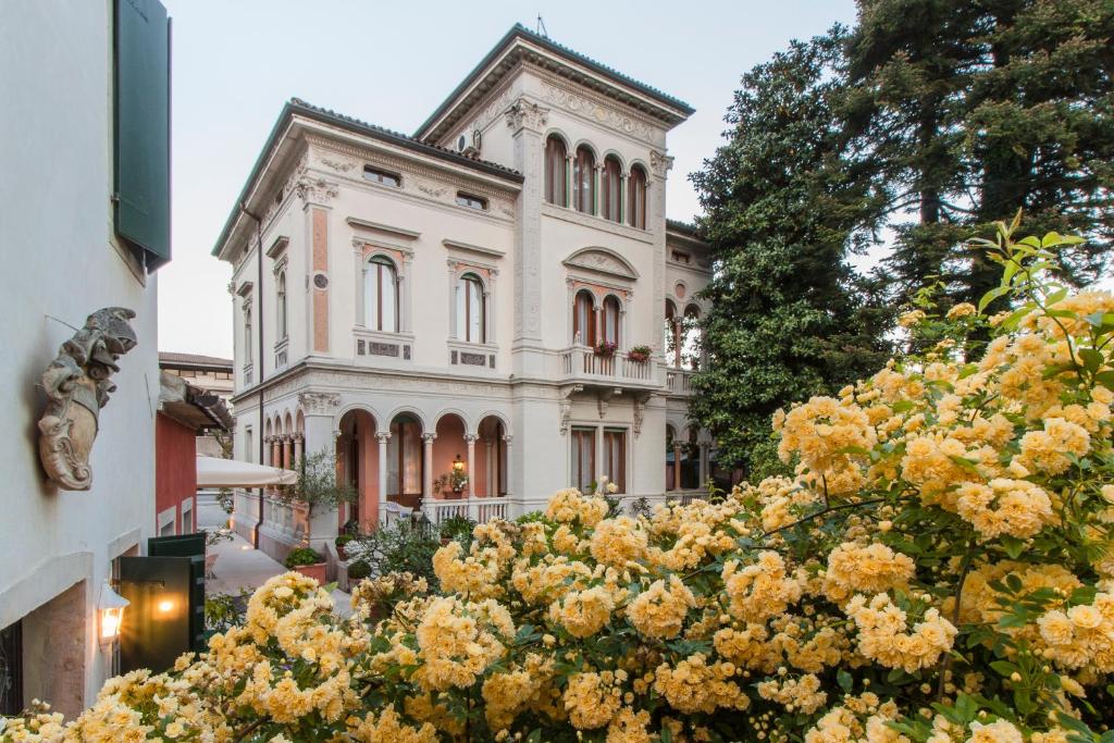 a large building with yellow flowers in front of it at Villa Abbazia Relais & Chateaux in Follina