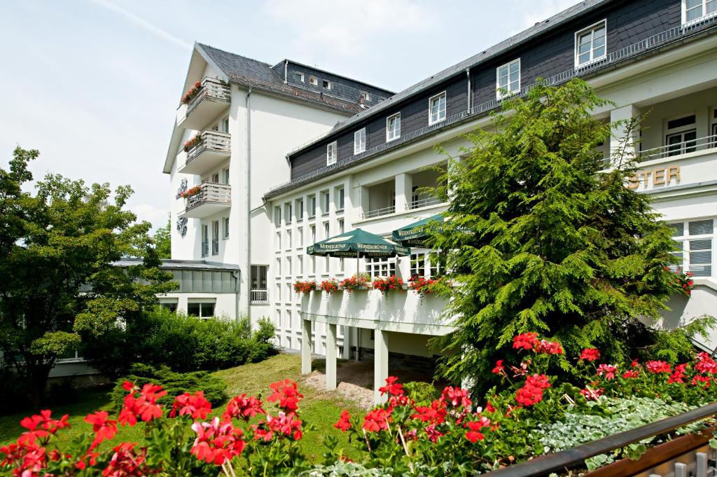 a hotel with red flowers in front of a building at Vitalhotel Weisse Elster in Bad Elster