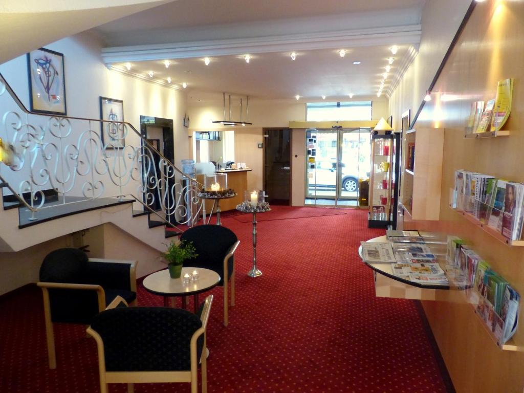 eine Bibliothek mit Stühlen, Tischen und einem roten Teppich in der Unterkunft City Hotel by celina in Hagen