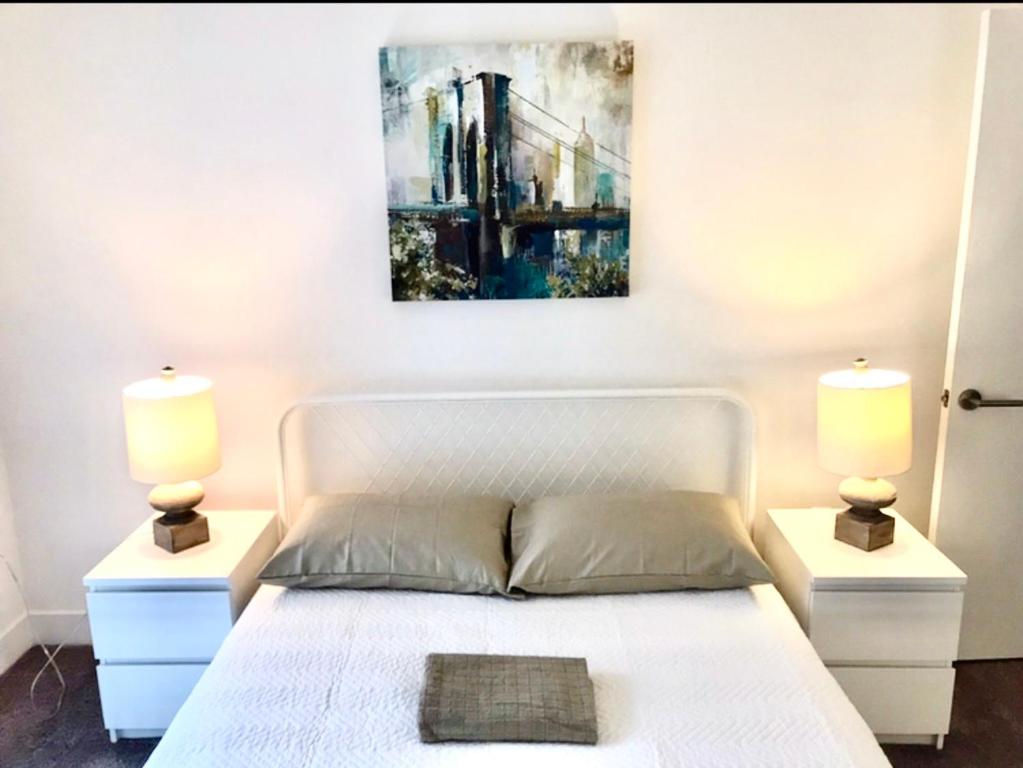 Un dormitorio con una cama blanca con dos lámparas. en Western Lemon Grove, en Los Ángeles