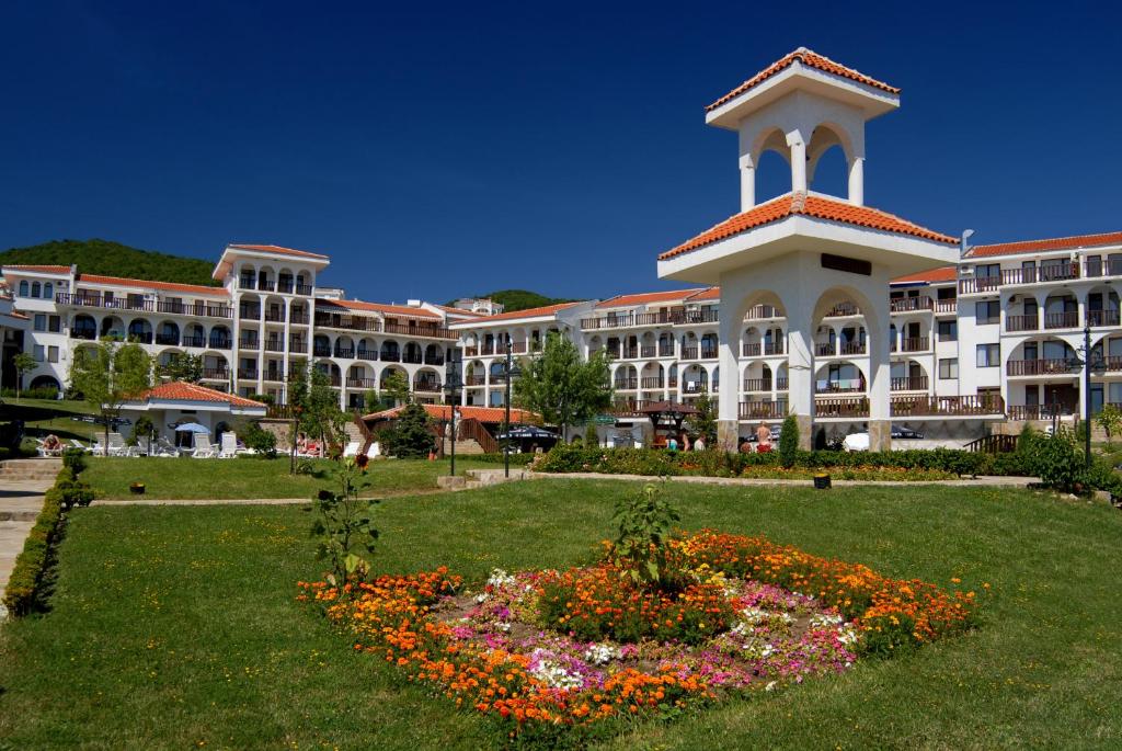 a large building with a clock tower in a park at KAMBANI BELLS Apart Complex in Sveti Vlas