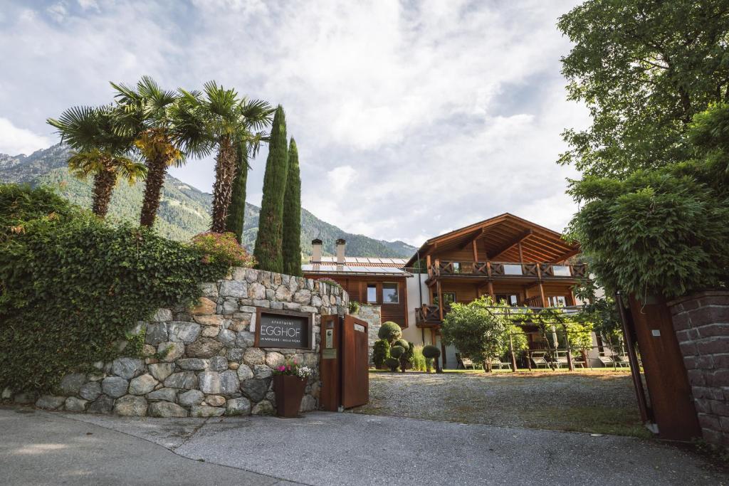 a house with a stone wall and palm trees at Apartment Egghof im Weingut in Merano