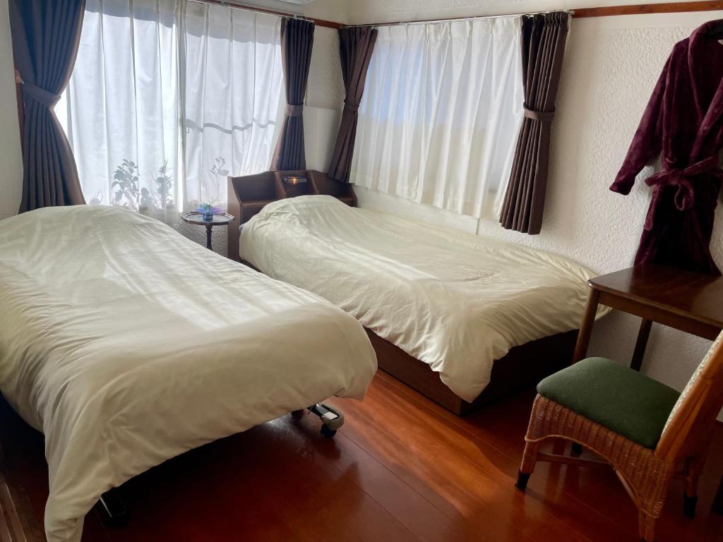 a bedroom with two beds and a chair and a window at Azumi Relax Lodge in Azumino