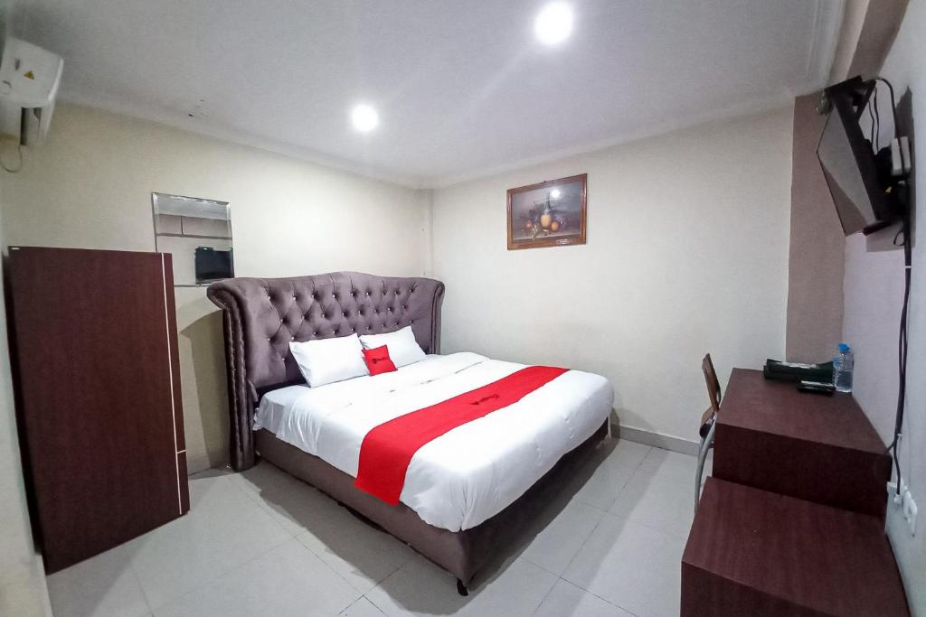 a bedroom with a bed with a red and white blanket at RedDoorz Hotel Baaraka near Living World in Pekanbaru