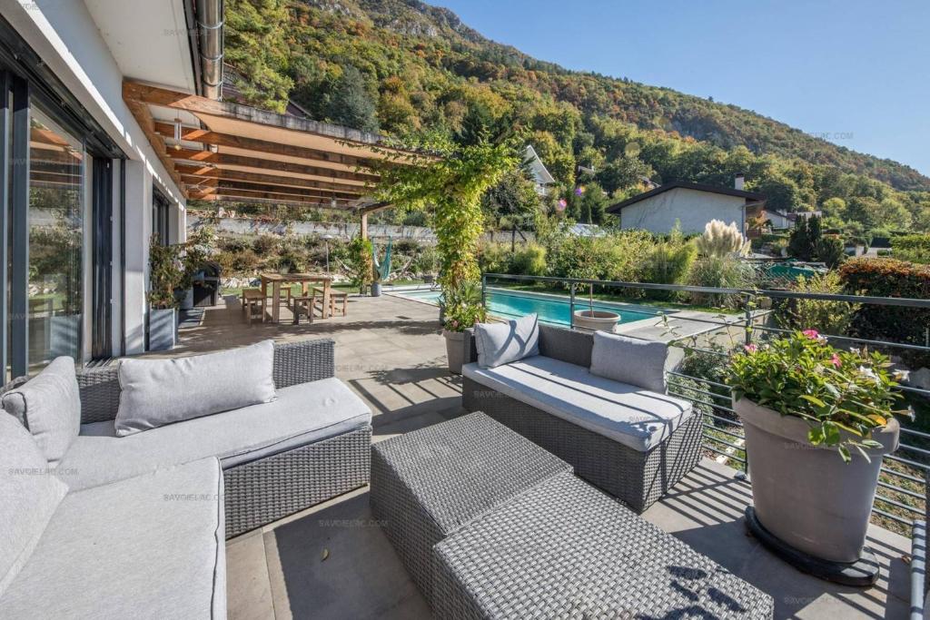 une terrasse avec mobilier en osier et une piscine dans l'établissement Annecy-le-vieux Villa Rainettes, à Annecy