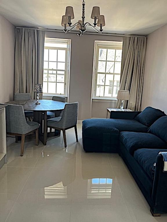 Hotel New Royal Mile Residence Quiet Spacious and Comfortable Flat with Great Views Top Floor No Lift, a living room with a blue couch and a table at New Royal Mile Residence Quiet Spacious and Comfortable Flat with Great Views Top Floor No Lift in Edinburgh