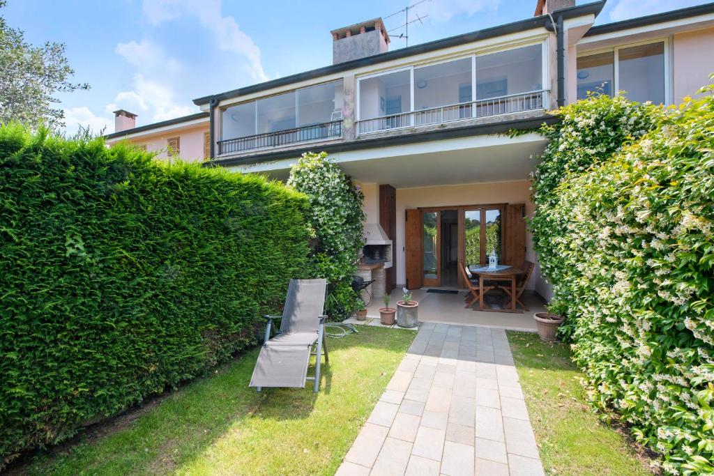 ein Haus mit einer Hecke und einer Bank im Hof in der Unterkunft Appartamento I Vigneti del Garda in Lazise