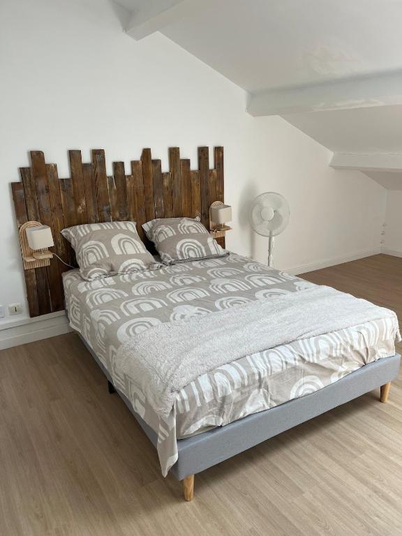 une chambre avec un grand lit avec une tête de lit en bois dans l'établissement Duplex T3 cosy, à Avignon