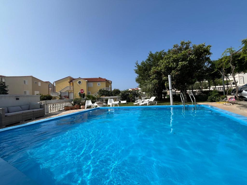 a large blue swimming pool in a yard at Apartments Božena in Vodice