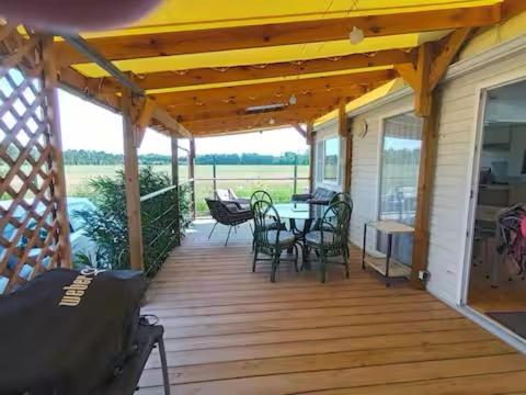 une terrasse couverte en bois avec une table et des chaises. dans l'établissement Logis de l'étangs, à Fréjus