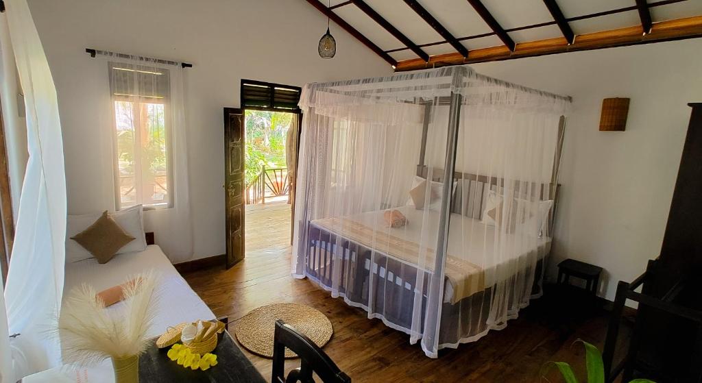 a bedroom with a bed with a mosquito net at Ginger Harmony Guesthouse and Cafe in Tangalle