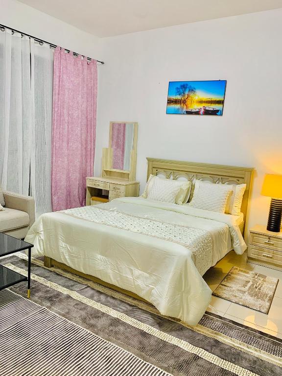 una camera con un grande letto bianco e una sedia di Chill Zone a Abu Dhabi