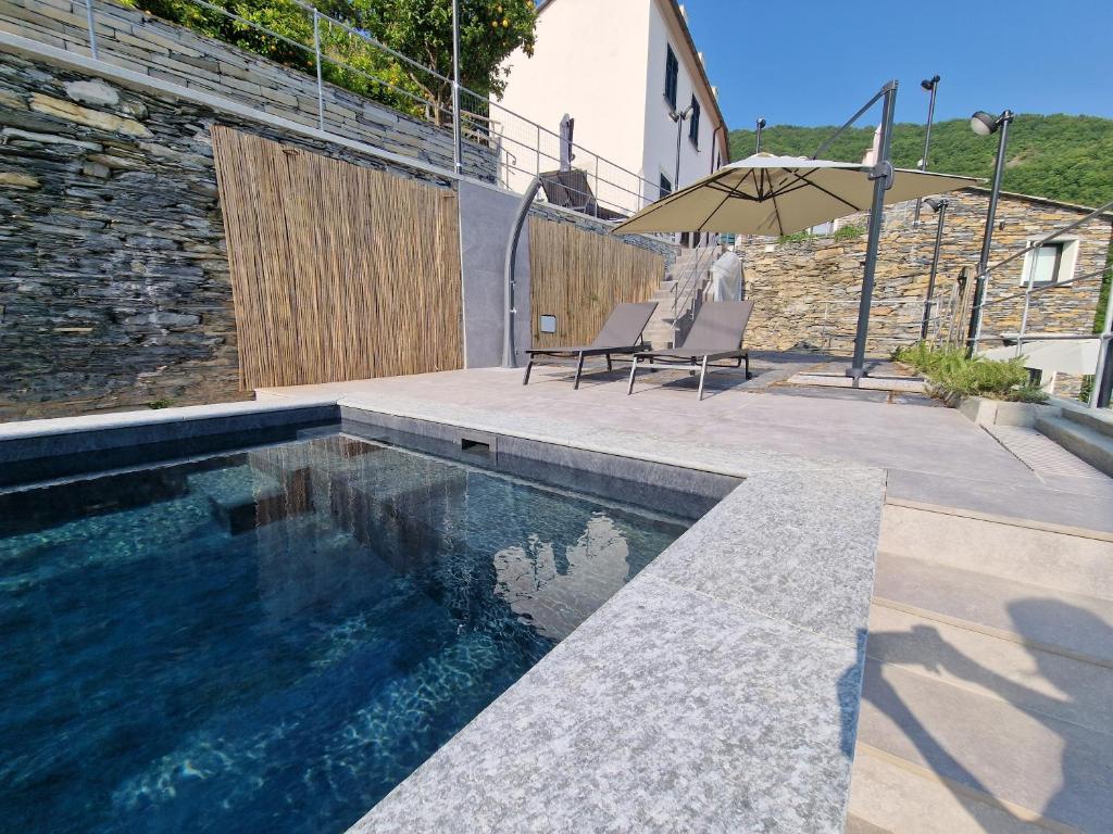 a swimming pool with two chairs and an umbrella at Dimore d'Oltremare - Appartamento Libeccio in Lavagna