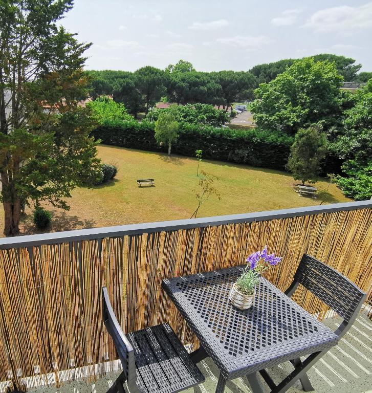 d'une table et de chaises sur un balcon avec un jardin. dans l'établissement Appartement Biscarrosse - Centre-ville, terrasse, au calme - agréable, tout confort - 4pers, à Biscarrosse