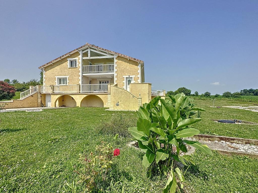 a large house in a field with a plant at Le relais - Groupe - BBQ - babyfoot - pingpong- netflix- clim in Horsarrieu