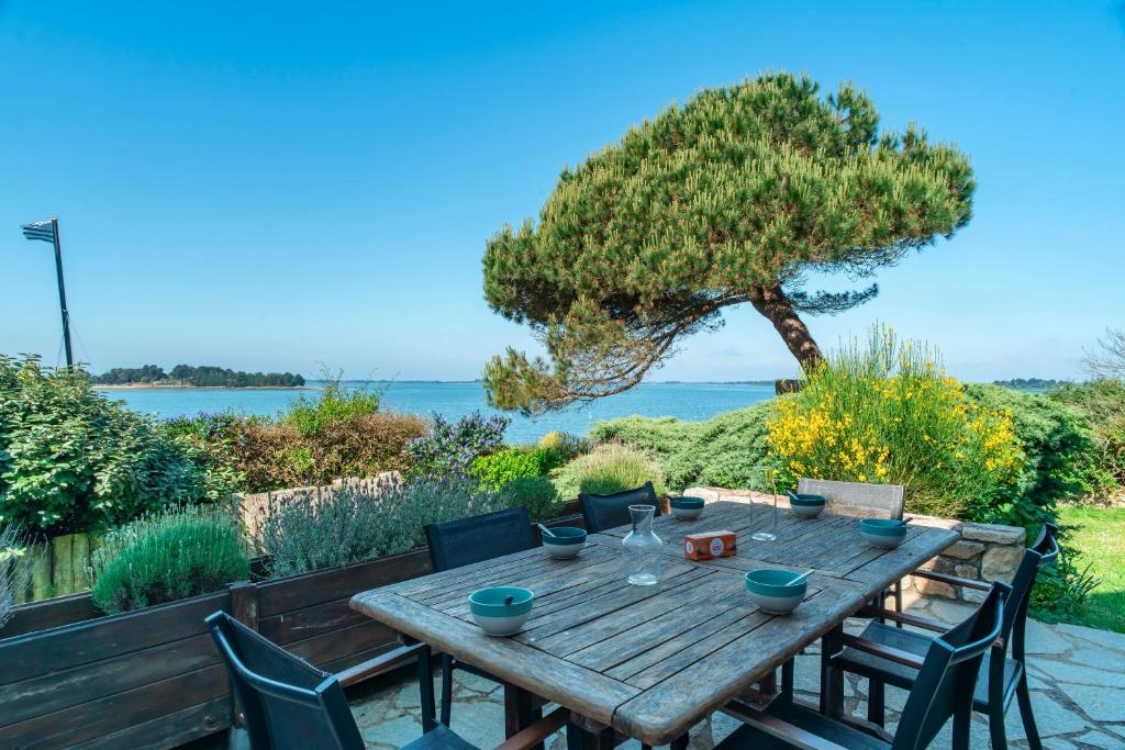 - une table en bois avec des chaises et une vue sur l'eau dans l'établissement Ker Doudou - Ile Tascon, à Saint-Armel