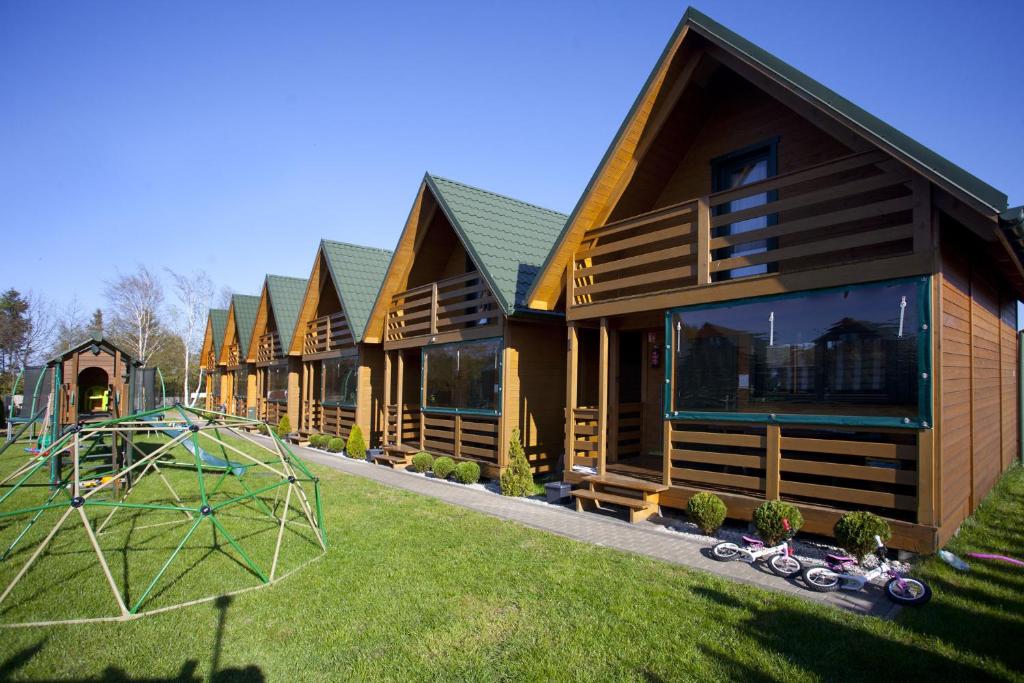 a row of log homes with a playground in the yard at Domki Tabaluga in Rusinowo