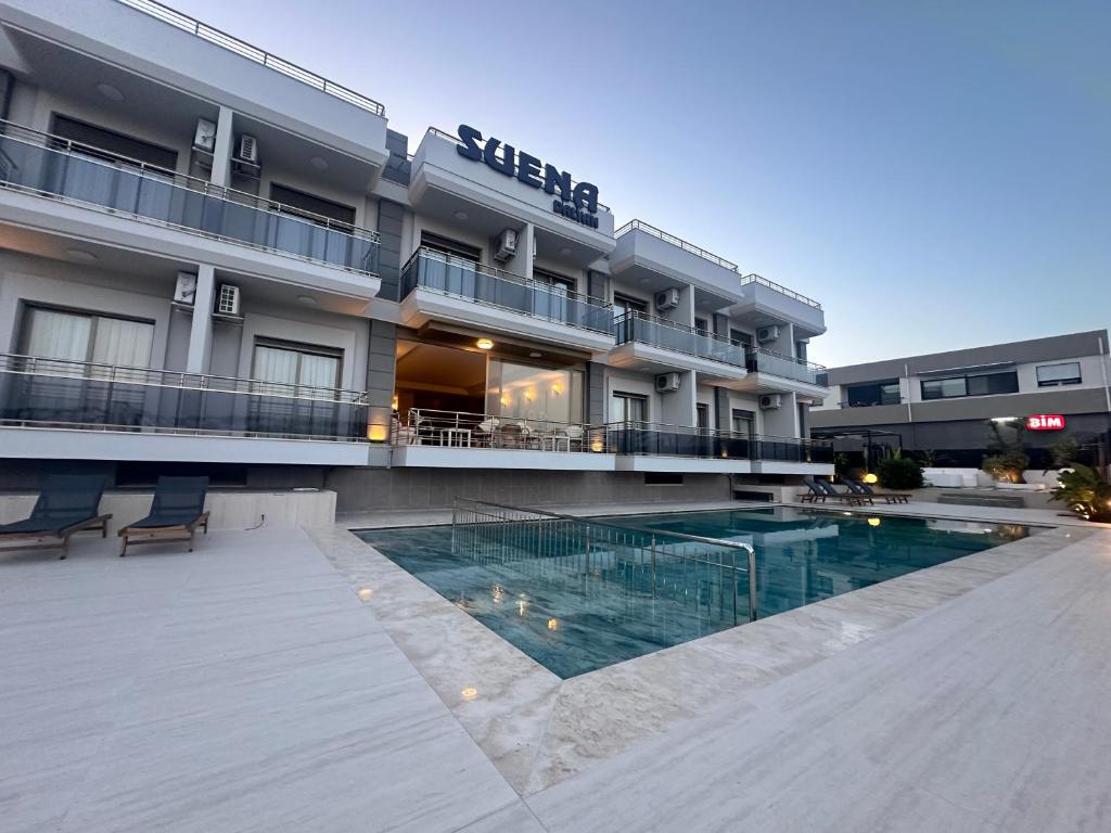 a hotel with a swimming pool in front of a building at SUENA HOTEL Çeşme in Çeşme