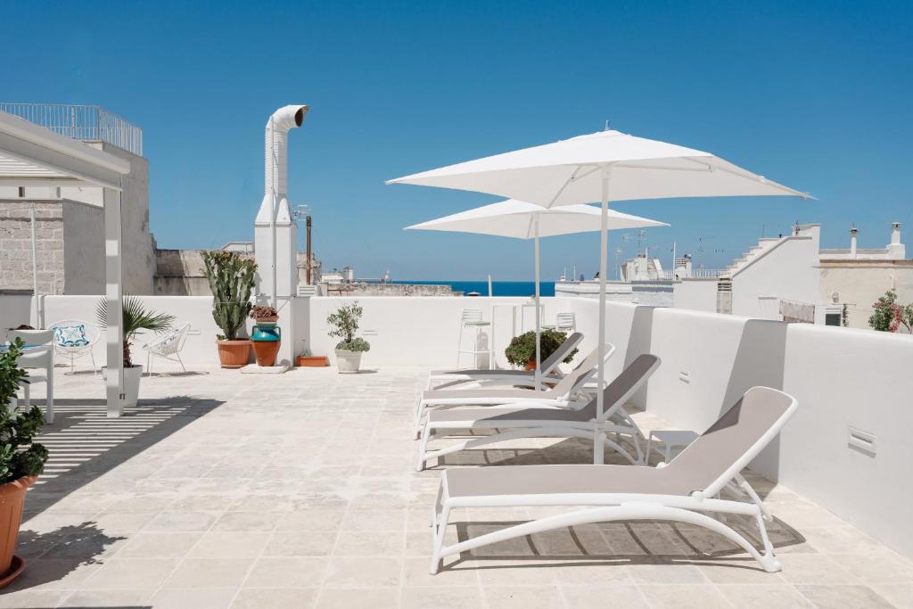a row of white chairs and an umbrella on a roof at Donna Domenica Boutique Suites in Polignano a Mare