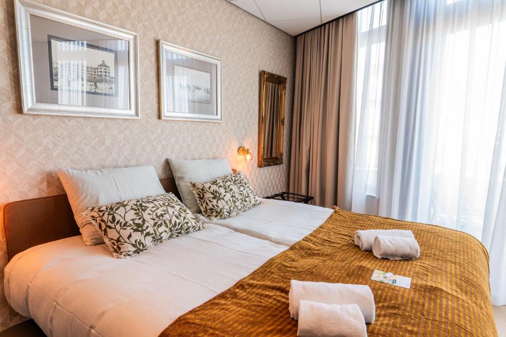 een slaapkamer met een groot bed met kussens erop bij Two Brothers Noordwijk Beach in Noordwijk aan Zee