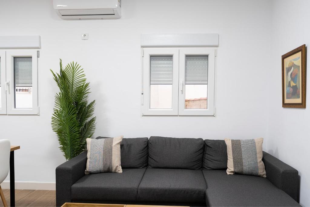 a living room with a couch and two windows at Altozano la Victoria A 2 hab in Andújar