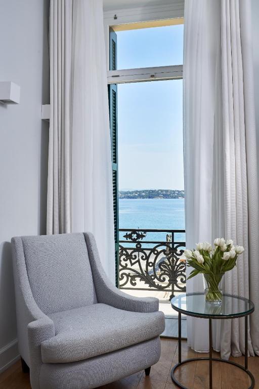 a living room with a chair and a table and a window at Poseidonion Grand Hotel in Spetses