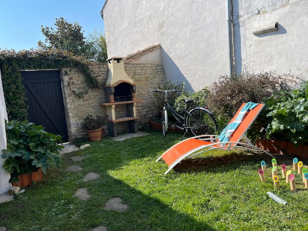 une cour avec un toboggan orange et un four à pizza dans l'établissement Chez Manon & David, à La Flotte