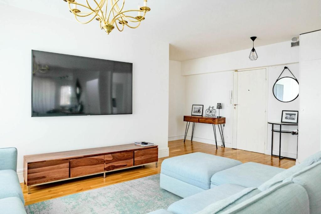 un salon avec un canapé et une télévision dans l'établissement Appt with Eiffel Tower view at Paris La Defense, à Puteaux