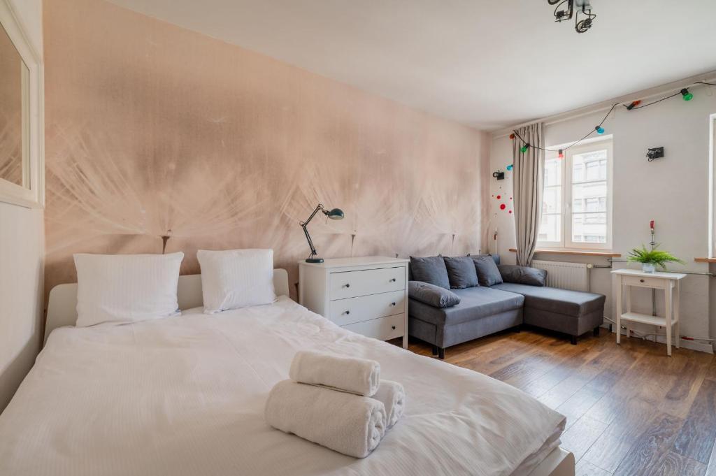 a bedroom with a large white bed and a couch at RentPlanet - Studio Rynek Ratusz in Wrocław