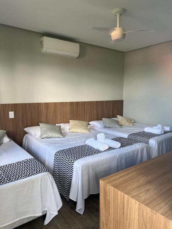 a group of three beds in a room at Suítes Aconchego in Capitólio