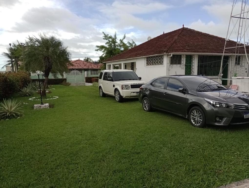 two cars parked in a yard in front of a house at Belíssima casa de Praia in Salinópolis