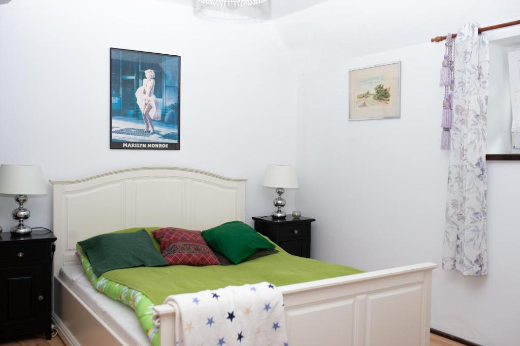 een witte slaapkamer met een bed met groene lakens bij Agroturystyka Podłazy 