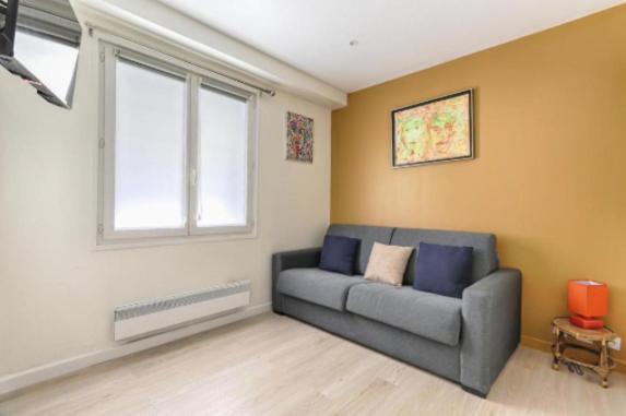 un salon avec un canapé et une fenêtre dans l'établissement Bastille Republique Charming & Cosy Apartment 1BR, à Paris