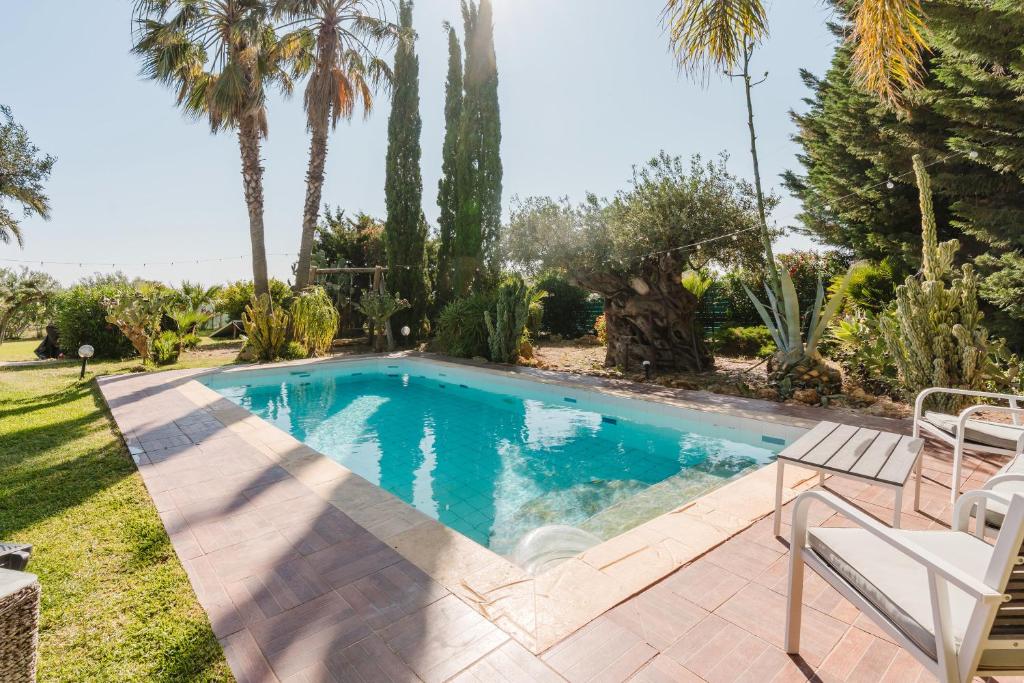 a swimming pool in a yard with palm trees at Casa Blandina in Menfi
