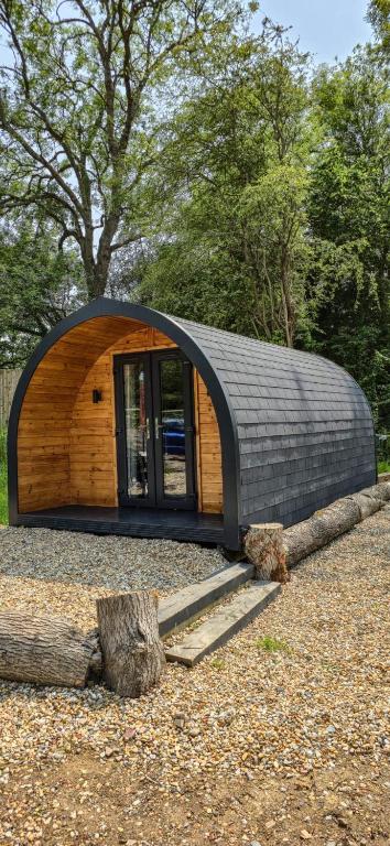 a small circular house with a black roof at Springfield oaks Glamping Pod in Isle of Wight