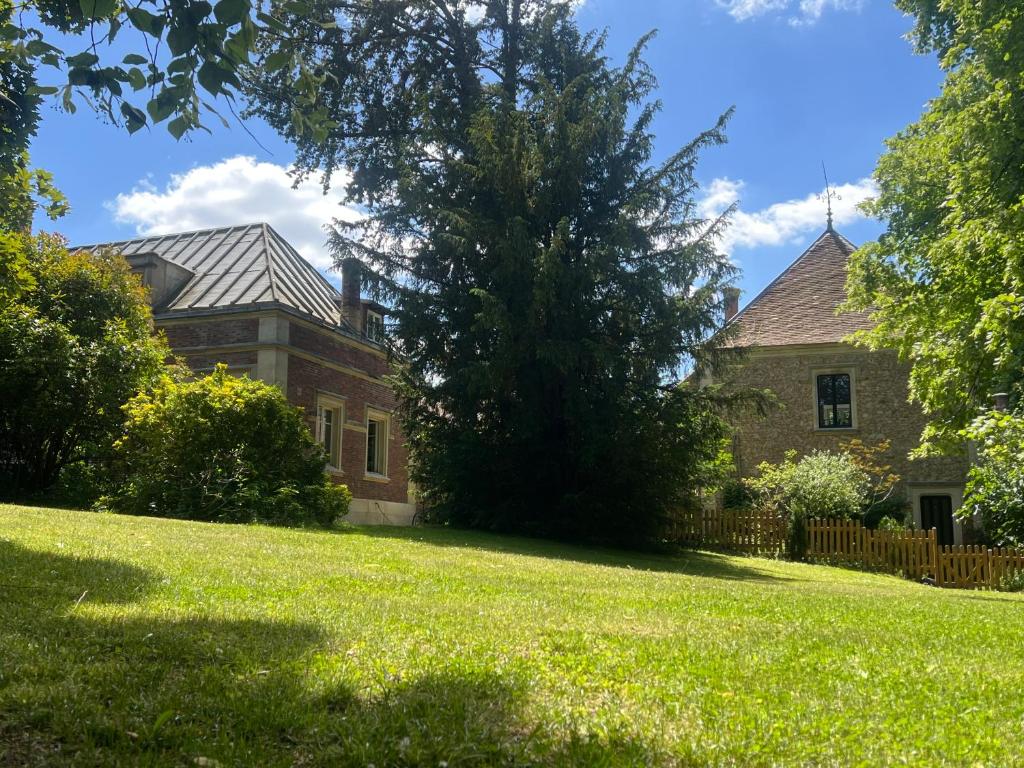 ein altes Backsteinhaus mit einem Baum im Hof in der Unterkunft Les écuries du château in Boissy-Saint-Léger