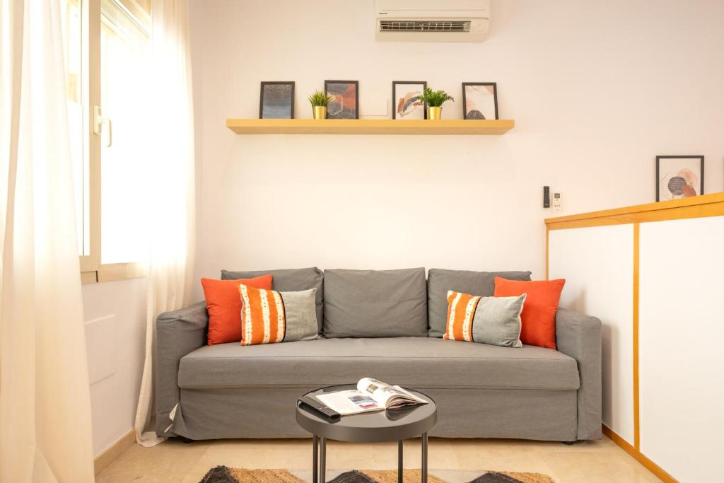 - un salon avec un canapé gris et des oreillers orange dans l'établissement ISG Apartments Estudio en La Alameda, à Séville