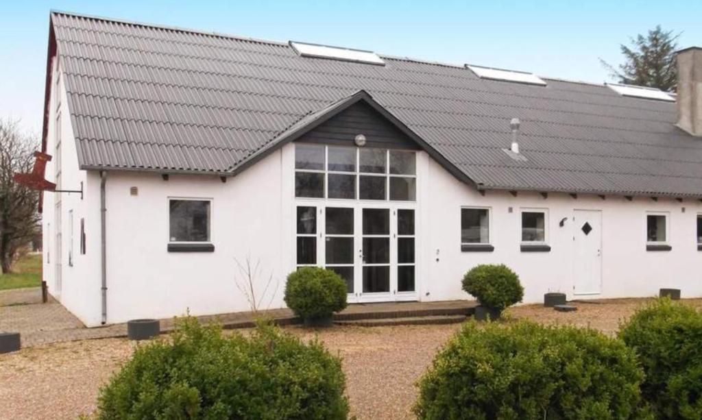 a white house with a black roof at Stort Aktivitets-Feriehus Med Fri Badeland, Bowling, Badminton Og Tennis, in Henne