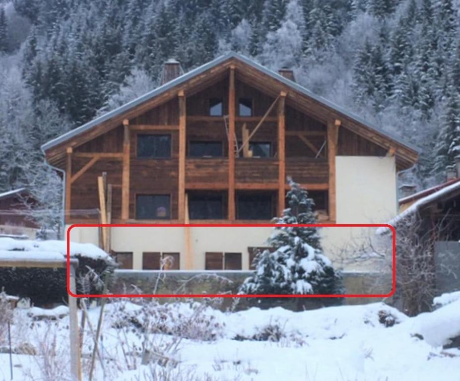 une grande maison en bois avec de la neige devant elle dans l'établissement La Pieuca, 50 m2 apartment in old farmhouse, aux Contamines-Montjoie