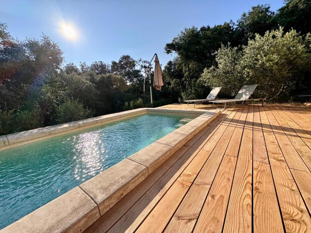 - une piscine avec une terrasse en bois et des chaises dans l'établissement Maison de Charme Uzes piscine 6 à 7 Personnes en pleine nature, à Saint-Siffret