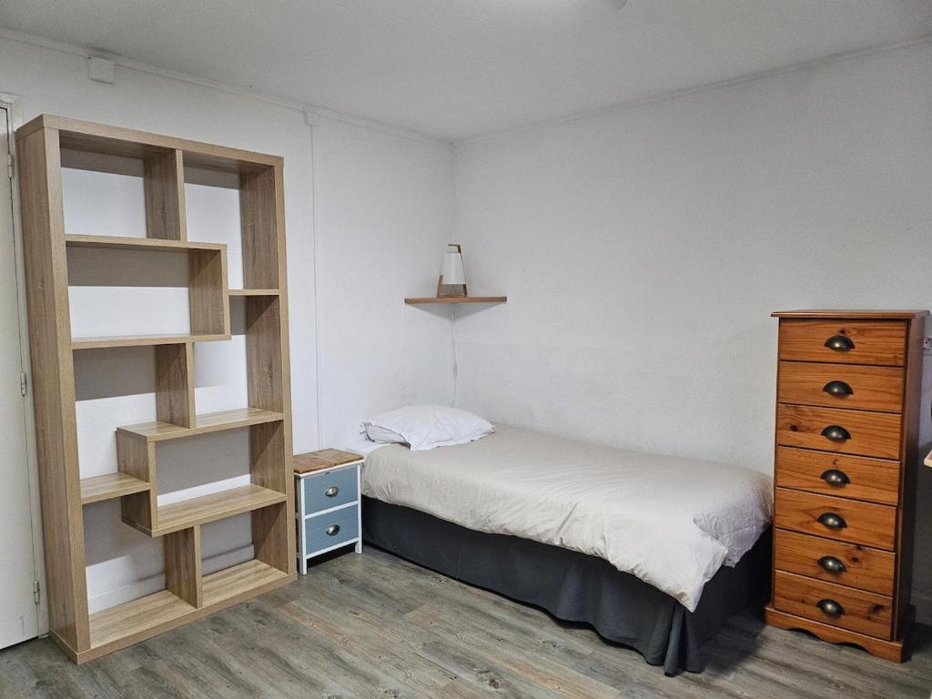 - une petite chambre avec un lit et une commode dans l'établissement Chambre meublée avec cuisine équipée, à Vic-en-Bigorre